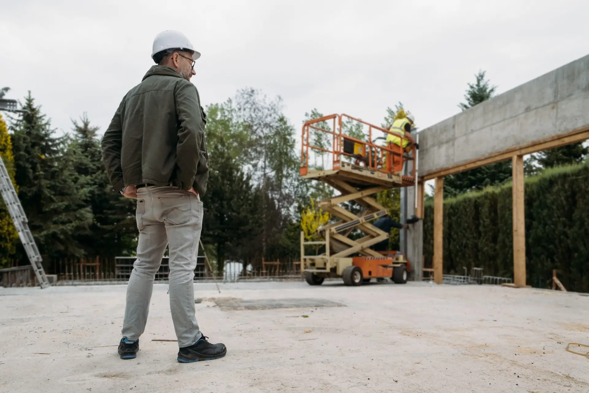 Scissor Lift Platform on a construction site. Building concreate house with mobile transportation vehicles. Industrial machine for work on height