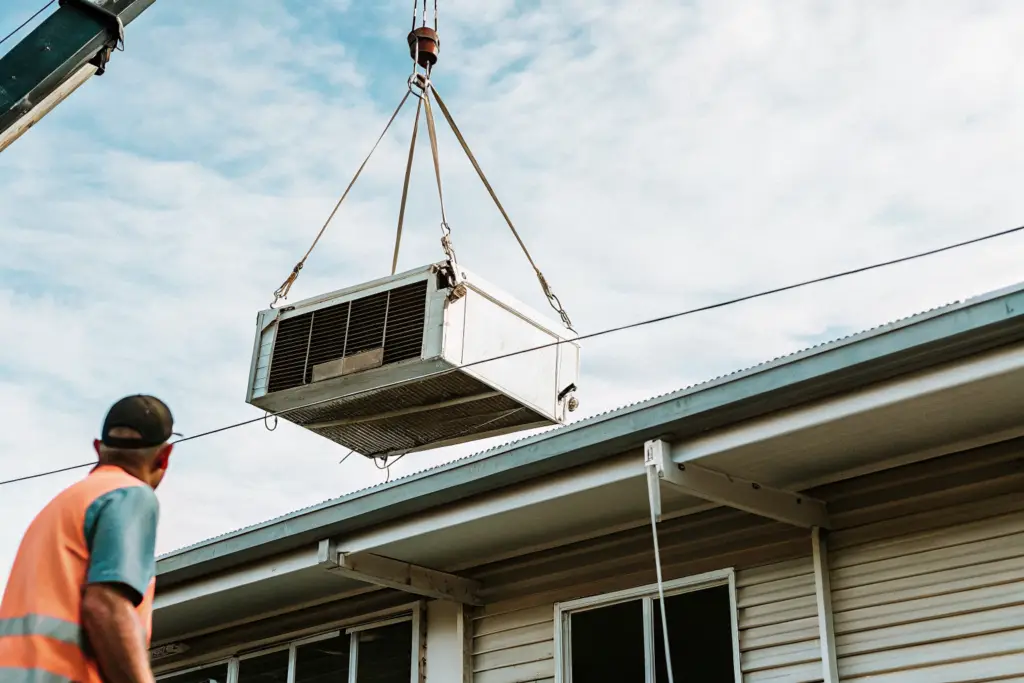 Crane lifting an air conditioning unit on slings - crane hire cost melbourne